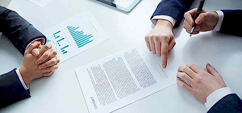 E-ticaret belgeleri bulunur masanın üstünde elinde kalem olan kolların yanında